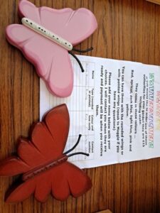 Pink butterfly-shaped clip resting on a notebook page with printed text on a wooden desk.